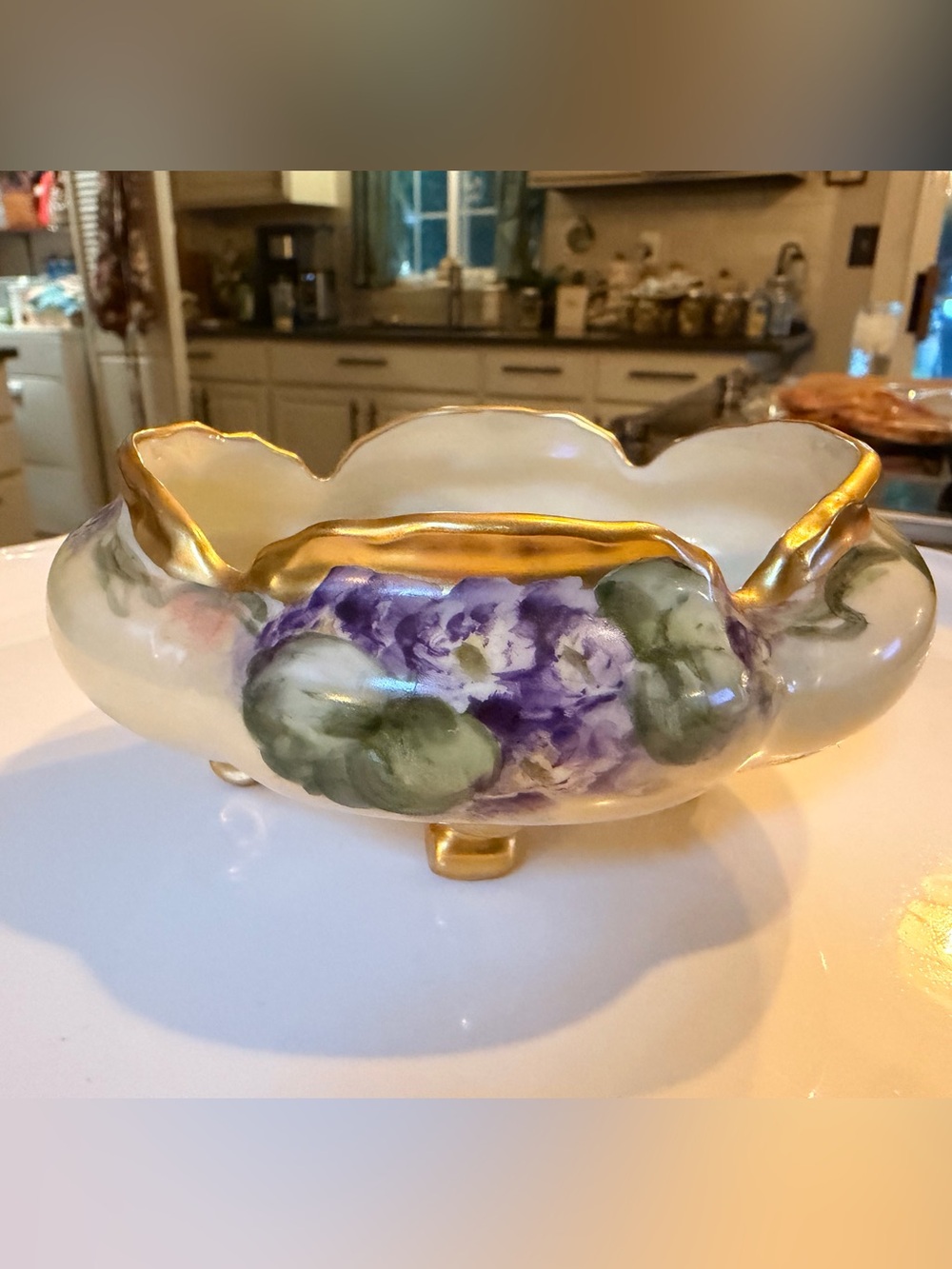 A hand-painted porcelain footed bowl with gilded rim and floral
decoration.